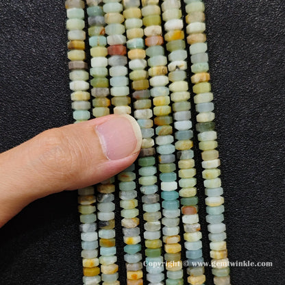 Close up view of 6x3mm amazonite faceted disc rondelle beads inspected on fingers for quality preview