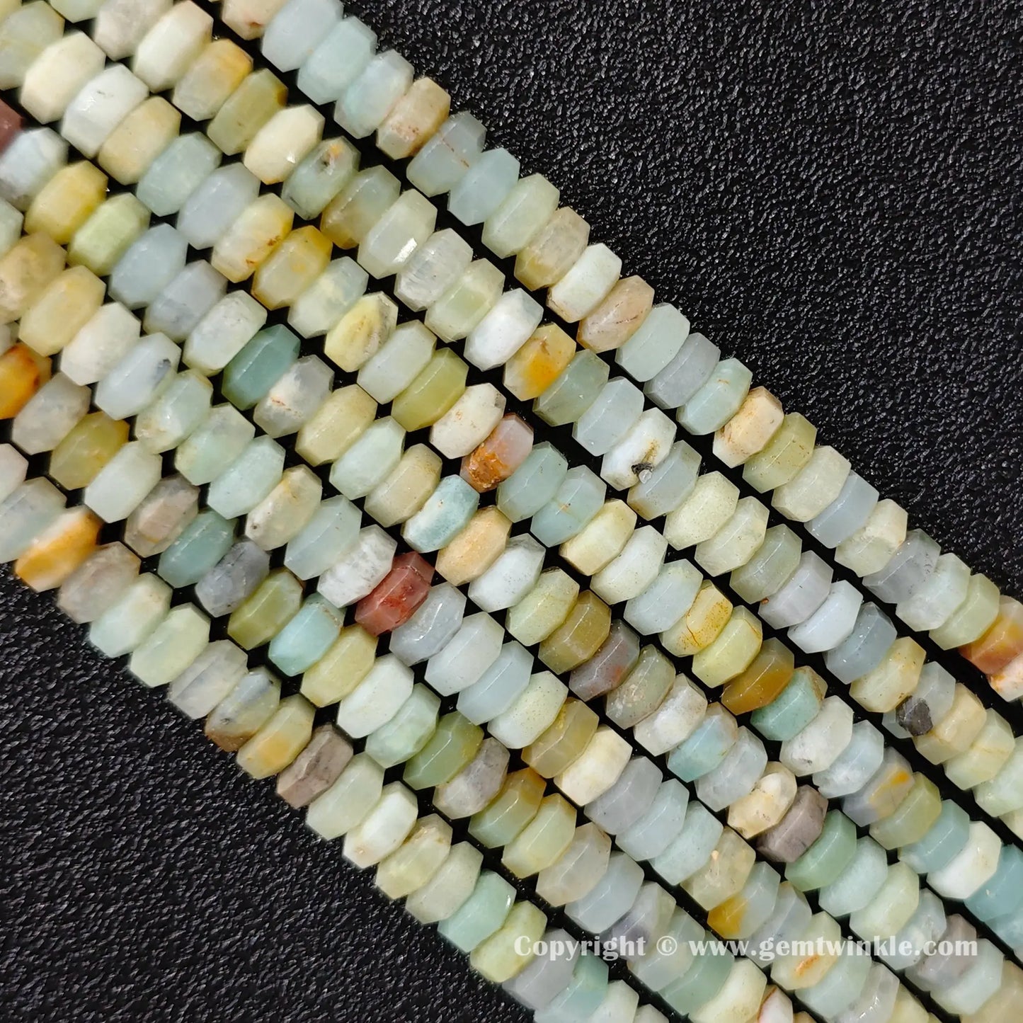 Angled view of natural amazonite faceted disc gemstone strands arranged parallel on dark background