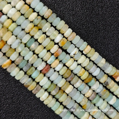 Angled view of natural amazonite faceted disc gemstone strands arranged parallel on dark background