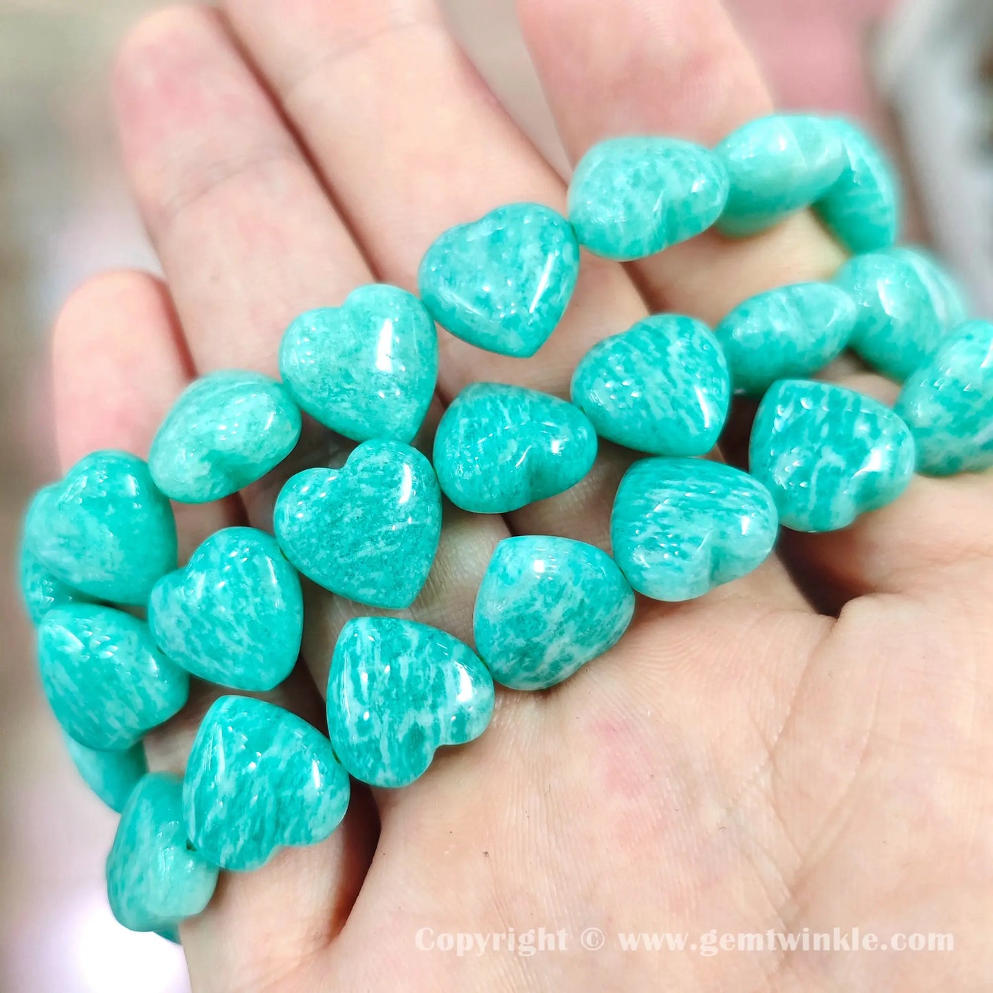 Close up handheld view of precision carved amazonite heart bracelet color contrast and finish