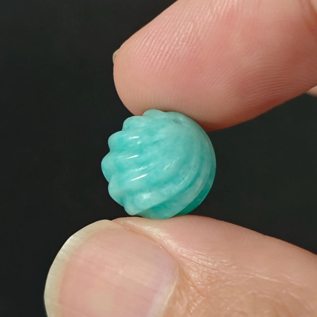 Amazonite spiral grooved bead 12-13mm held in fingers showing carved threaded lines and ocean teal blue tone