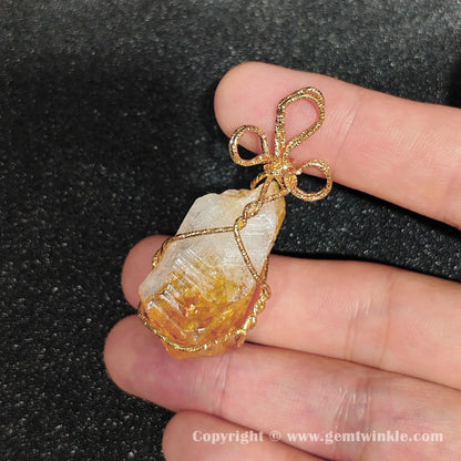 Close up view of golden amber citrine quartz nugget enclosed within gilded-tone wire frame