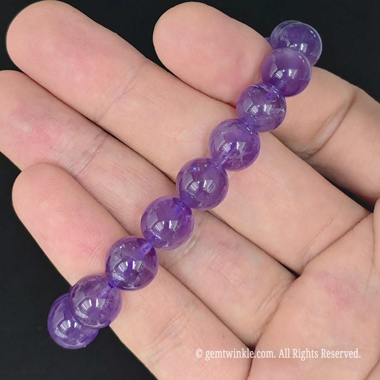 natural amethyst round bead strand laid flat across fingers
