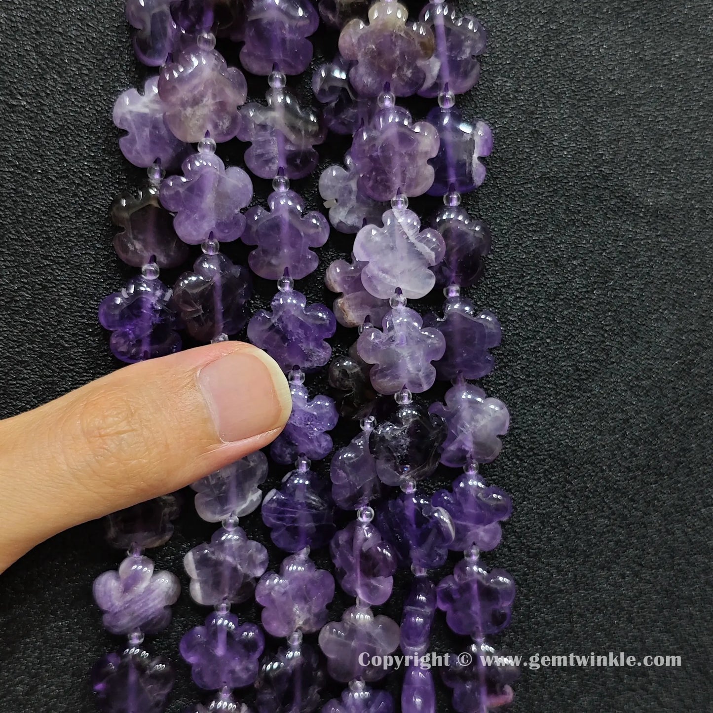 Natural amethyst quartz plum blossom carved bead strand held over hand showing size scale