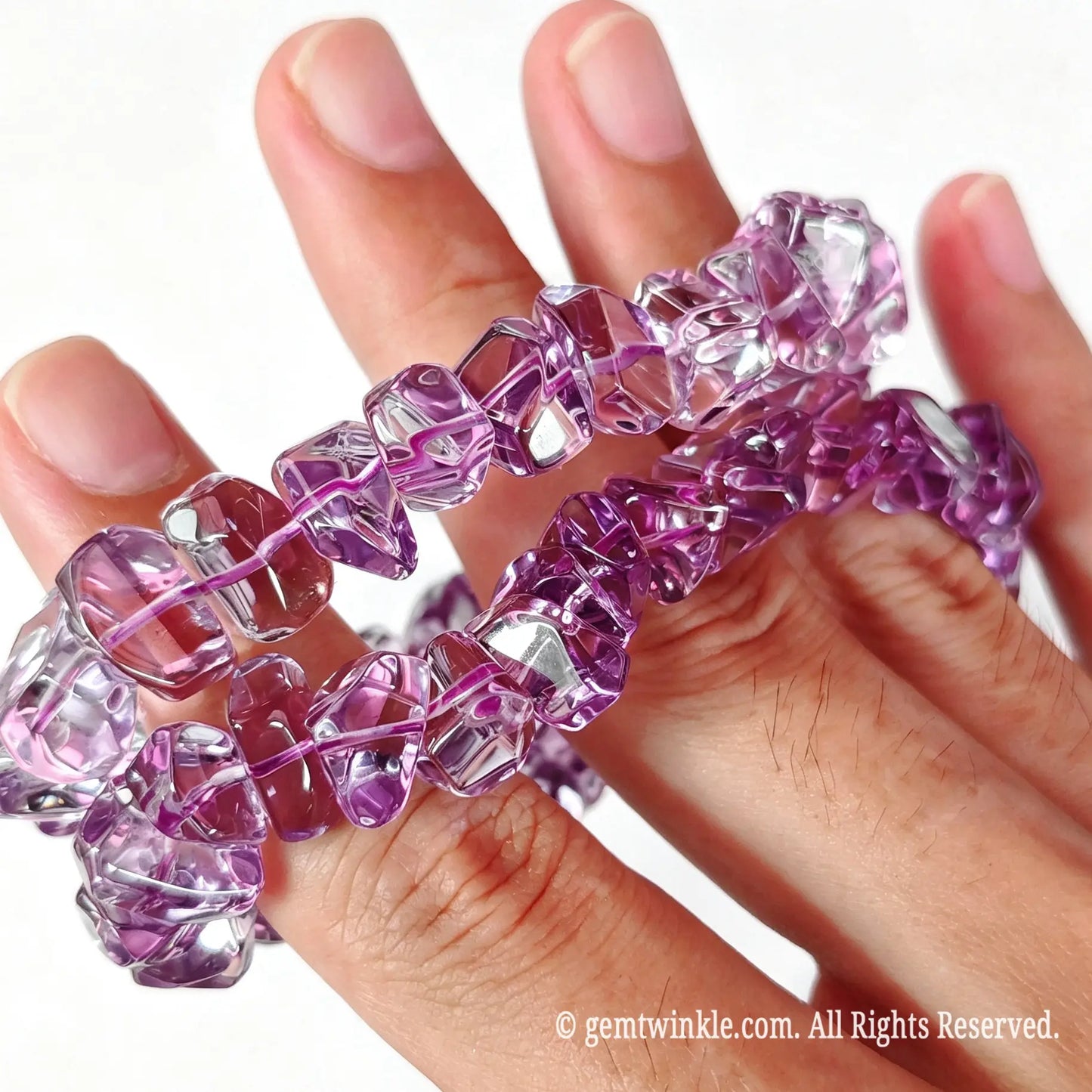 Side handheld view of high transparency amethyst chip stretch bracelets displaying glossy polish and light refractions