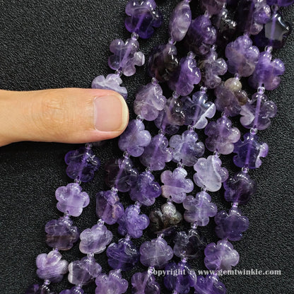 Close up view of amethyst plum blossom carved beads held on fingers for quality preview