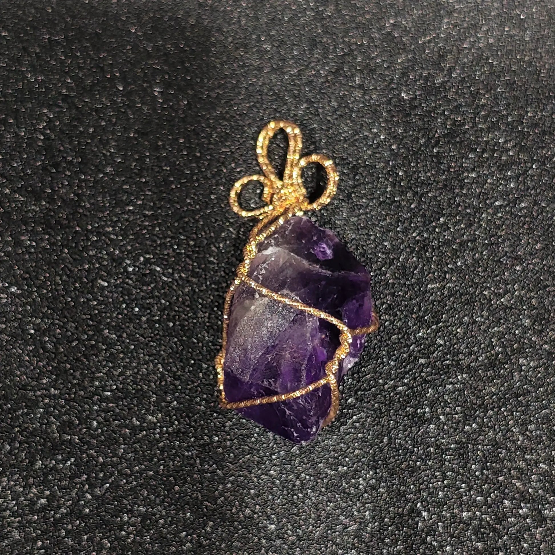 Raw purple amethyst crystal nugget with heavy cloud inclusions wrapped in gold-tone craft wire