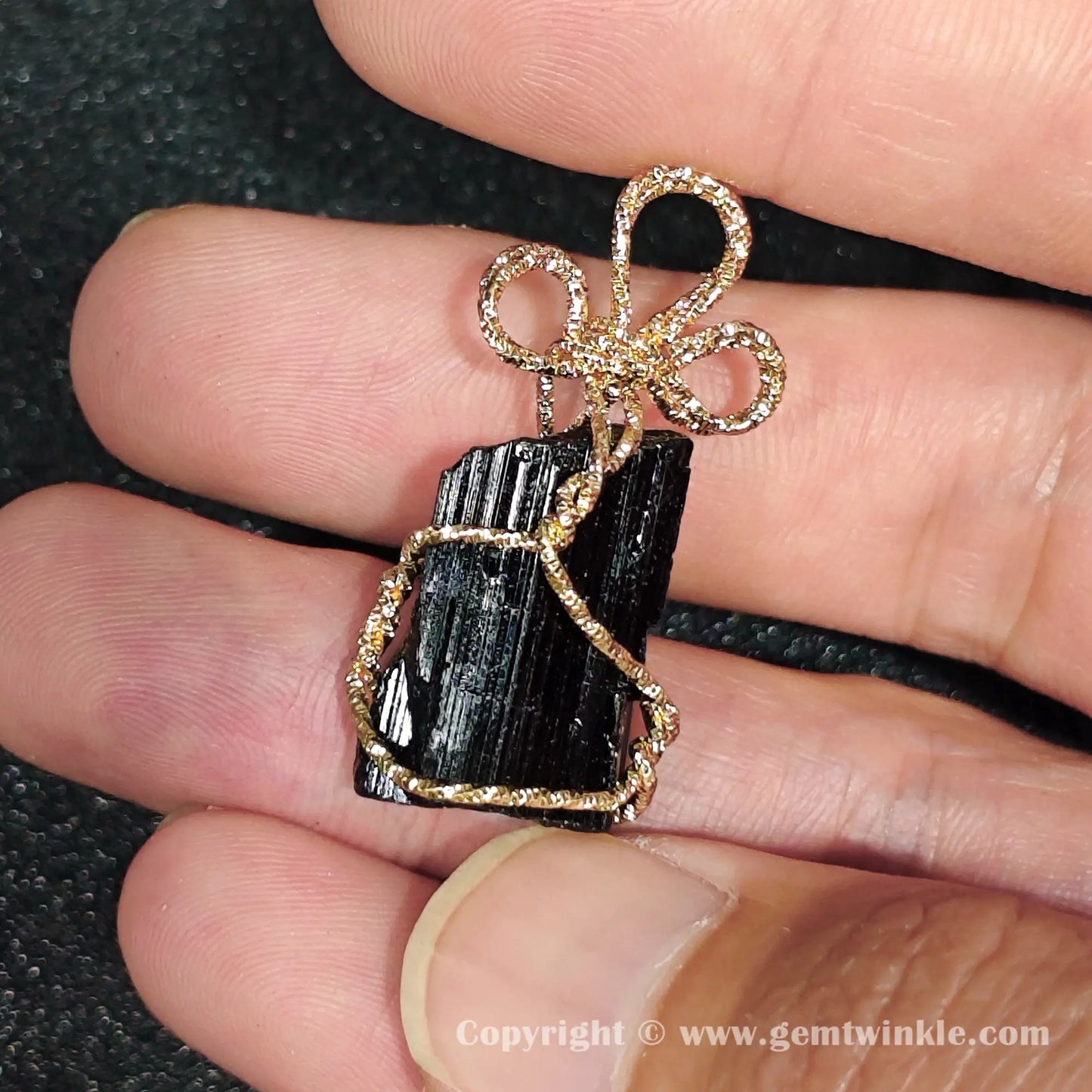 Angled preview of raw black tourmaline wire wrapped pendant showcasing gold-tone decorative top loop