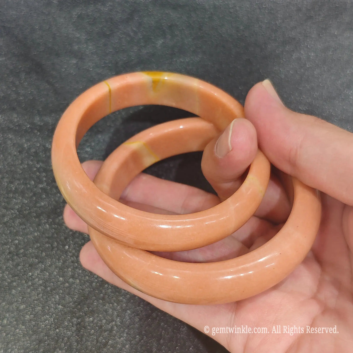 Side profile of smooth polished cinnamon orange stone bangle showing solid round thickness