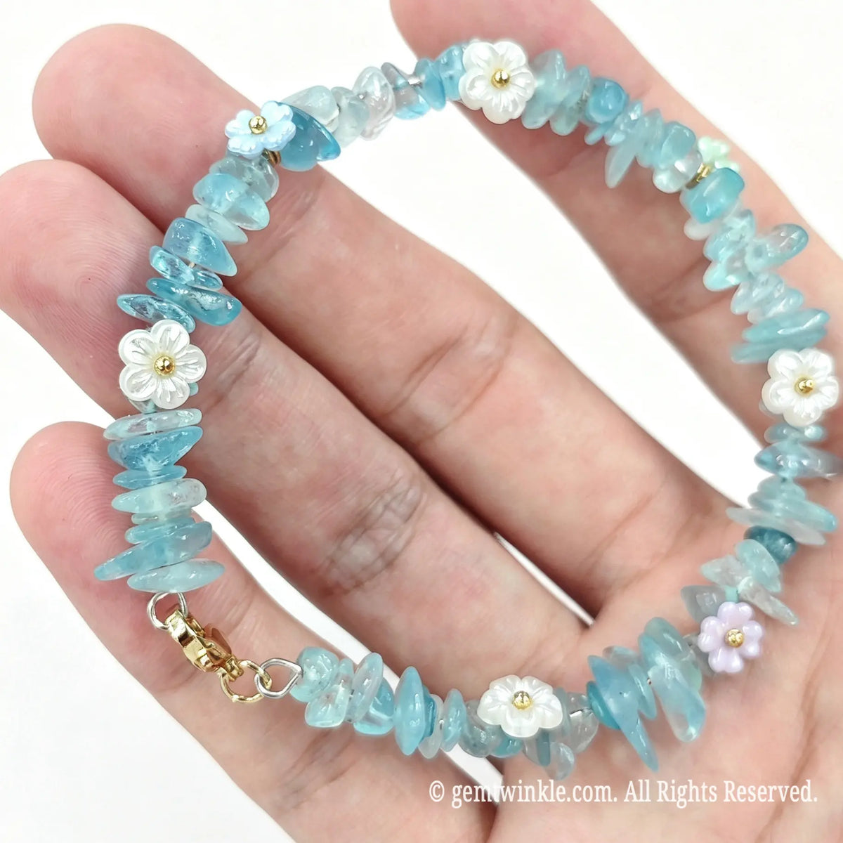 Hand preview of aquamarine chip wire-beaded bracelet with soft blue hues and floral details