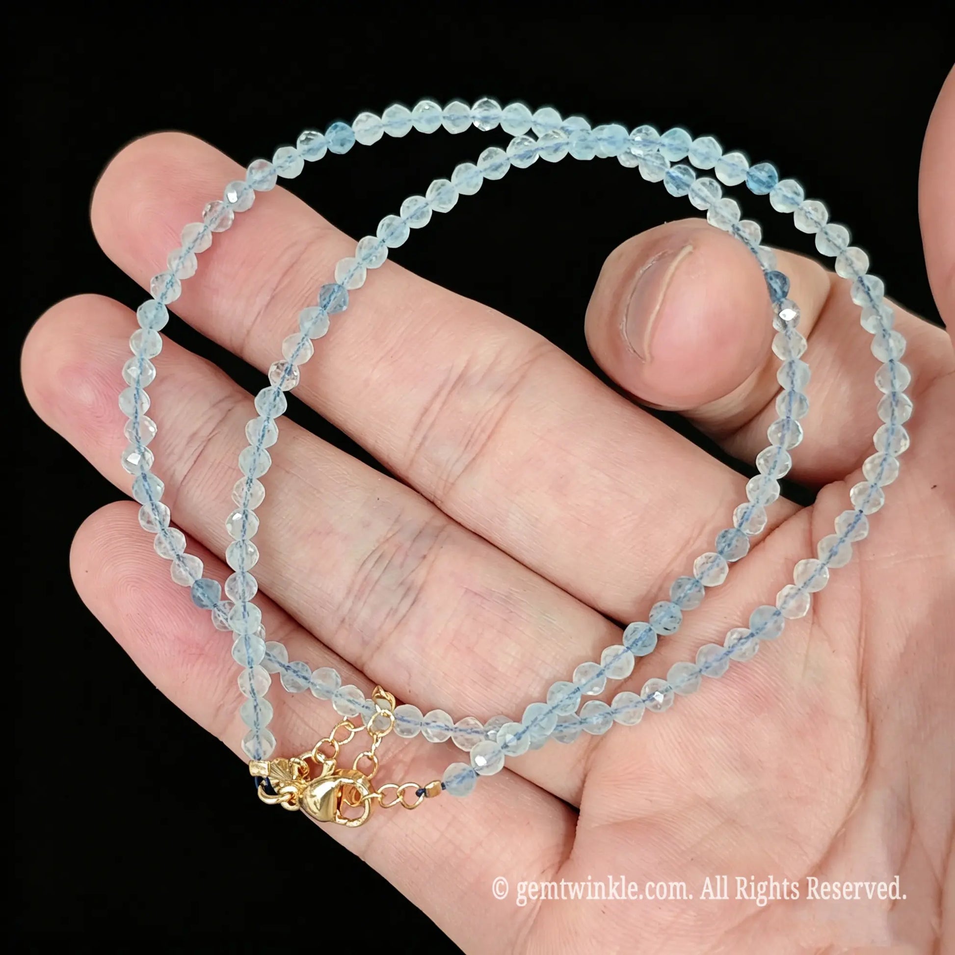 faceted aquamarine micro bead necklace loop with gold tone extender chain in hand