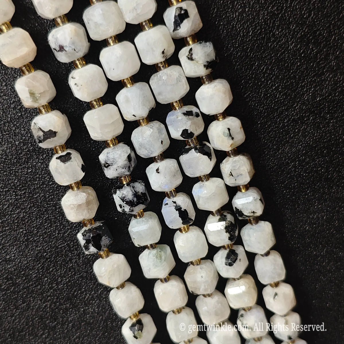 Designer hand holding black spot moonstone gemstone strands to demonstrate bead scale and polished luster