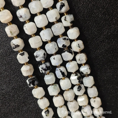 Designer hand holding black spot moonstone gemstone strands to demonstrate bead scale and polished luster
