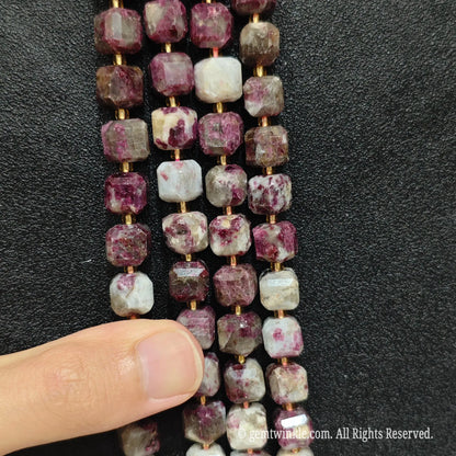 Designer hand holding tourmaline gemstone strands to demonstrate bead scale and polished luster
