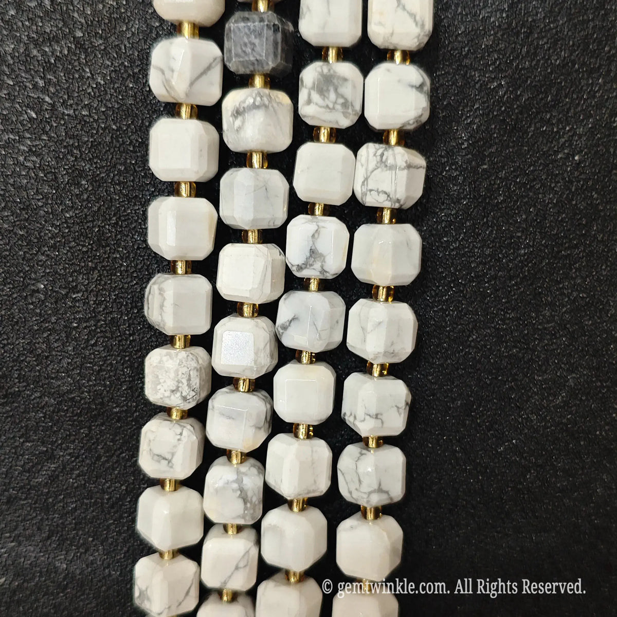 Designer hand holding white turquoise gemstone strands to demonstrate bead scale and polished luster