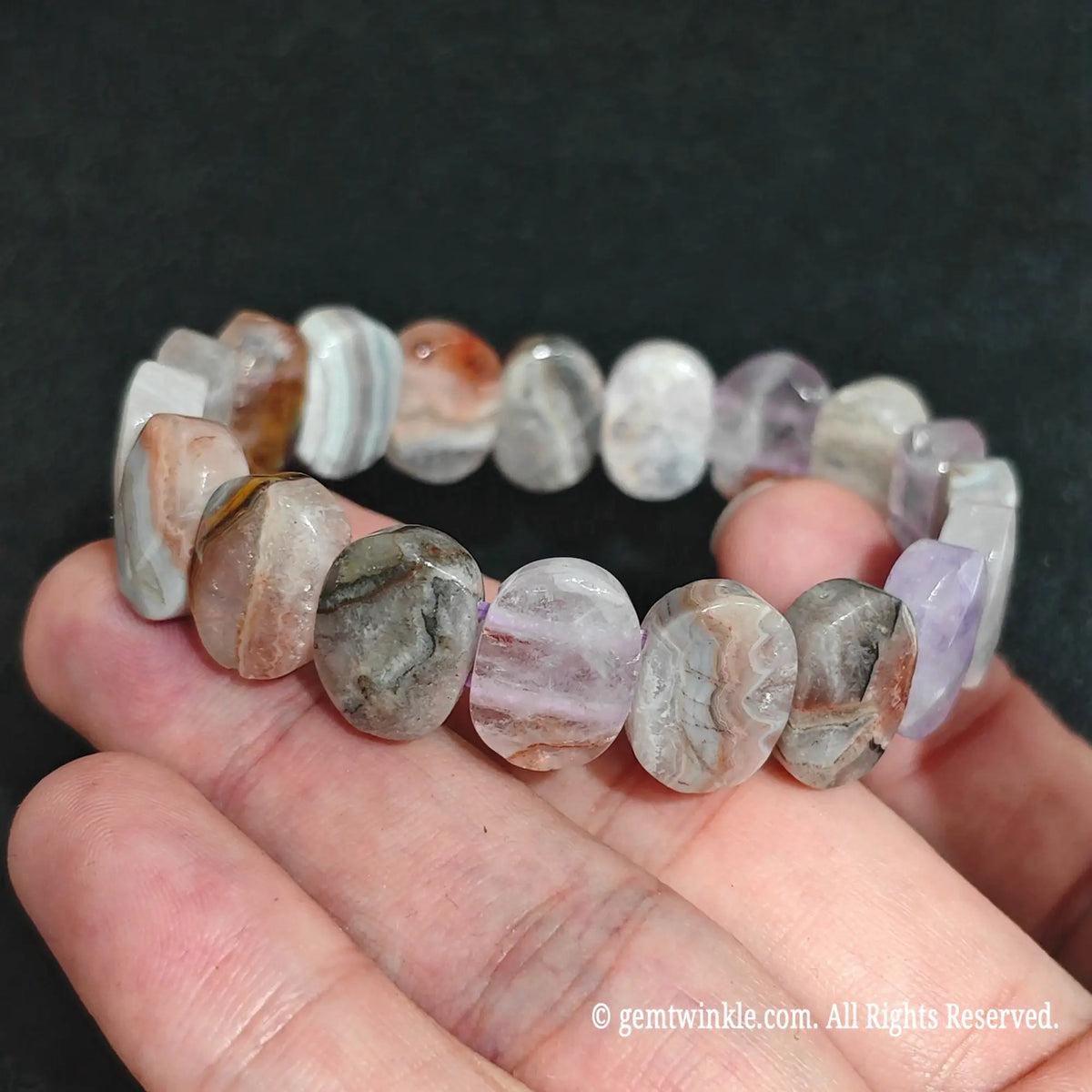Designer hand displaying a custom-sized amethyst agate stretch bracelet with rich mineral textures