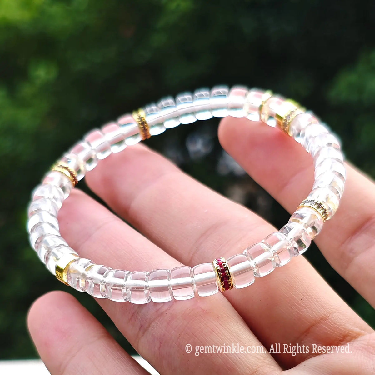 Designer hand displaying a high-purity clear quartz stretch bracelet with metallic copper accents