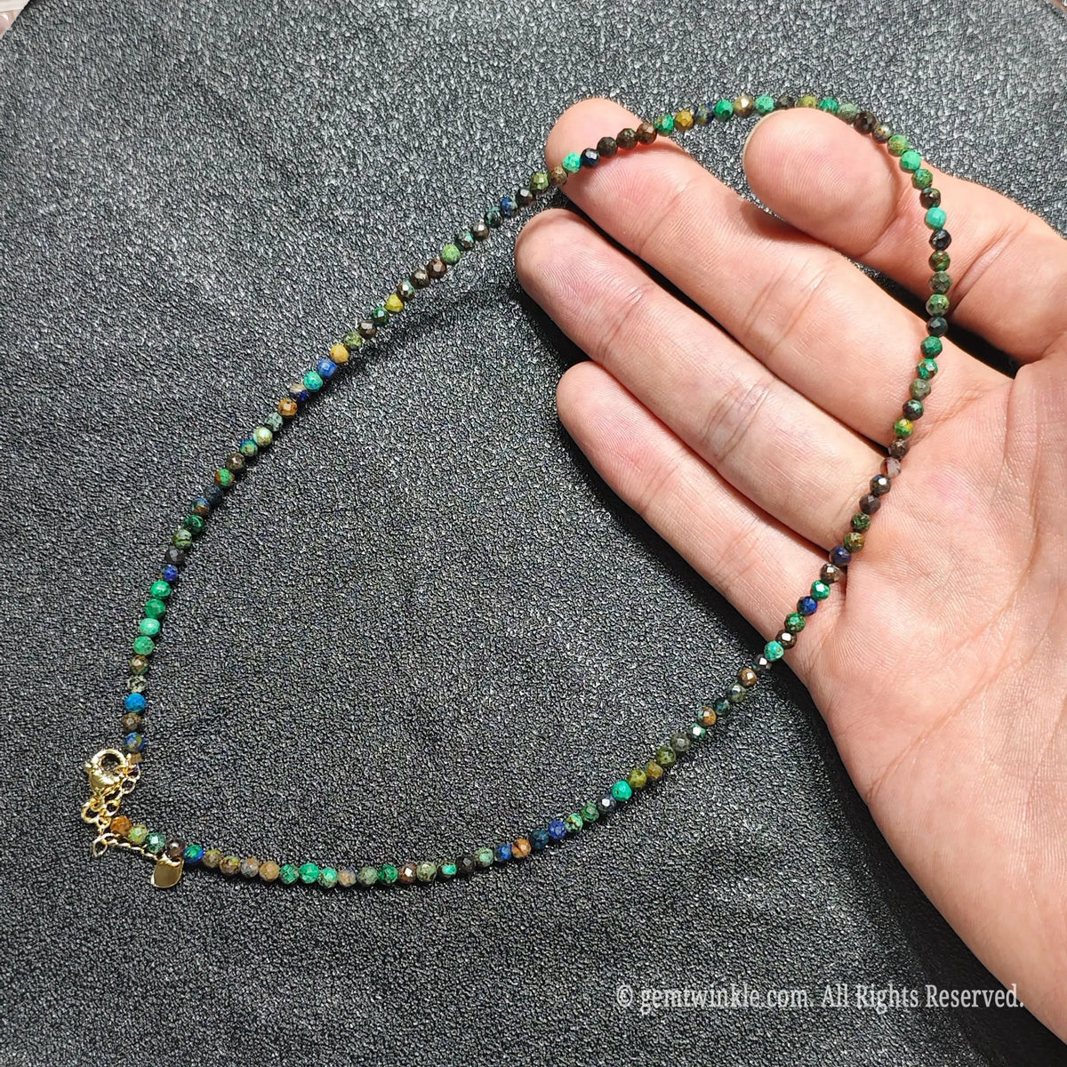 Hand holding 3mm faceted azurite malachite necklace showing blue and green copper mineral matrix and gold lobster clasp