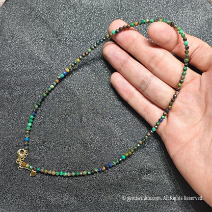 Hand holding 3mm faceted azurite malachite necklace showing blue and green copper mineral matrix and gold lobster clasp