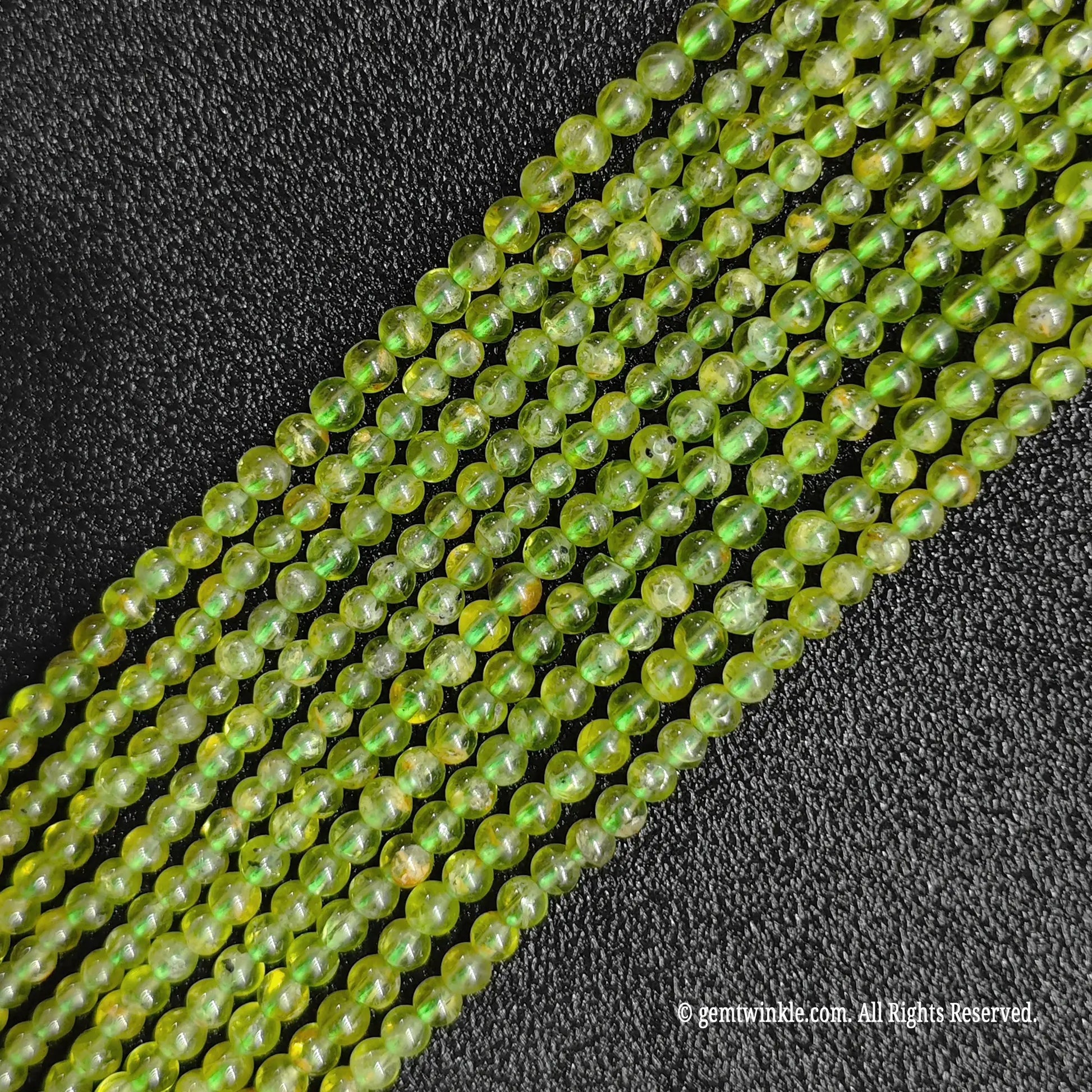 Close up view of commercial B-Grade tiny natural peridot strands from image_2a2720.jpg showcasing clear olive hues and smooth finishes