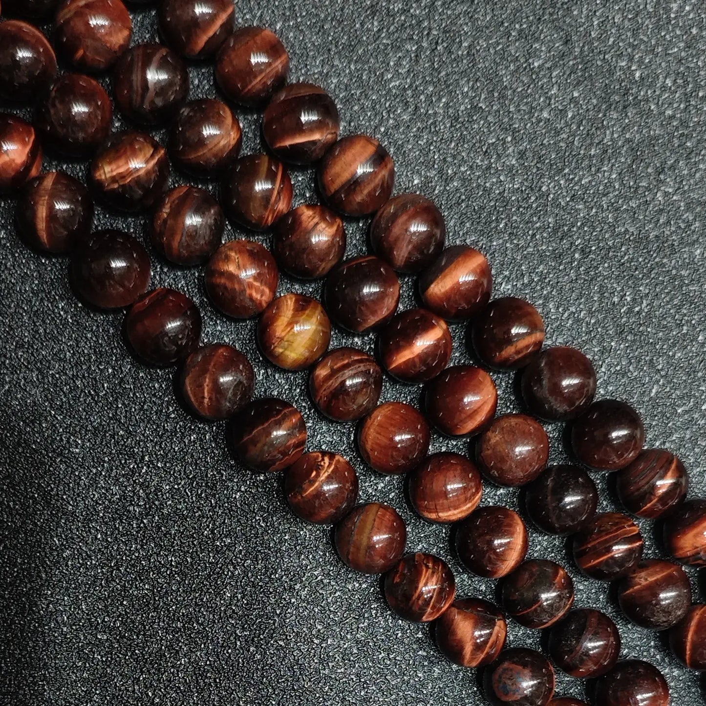 Close up of B minus grade red tigers eye round beads showing natural surface pits and ice cracks