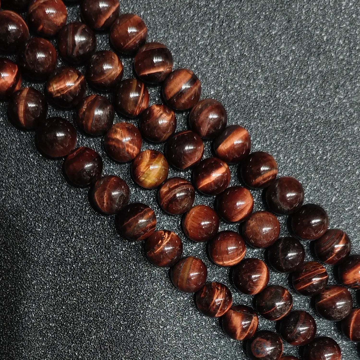 Close up of B minus grade red tigers eye round beads showing natural surface pits and ice cracks