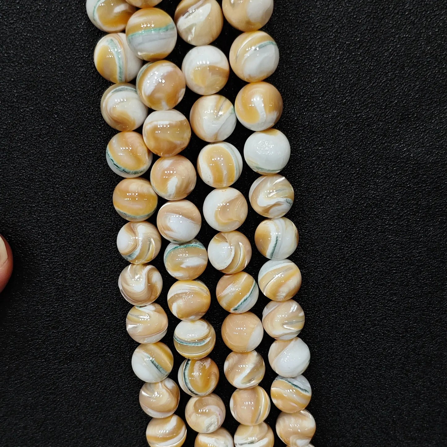 Four strands of un-dyed genuine natural spiral conch shell round beads for beaded bracelet supplies displayed by factory wholesale vendor