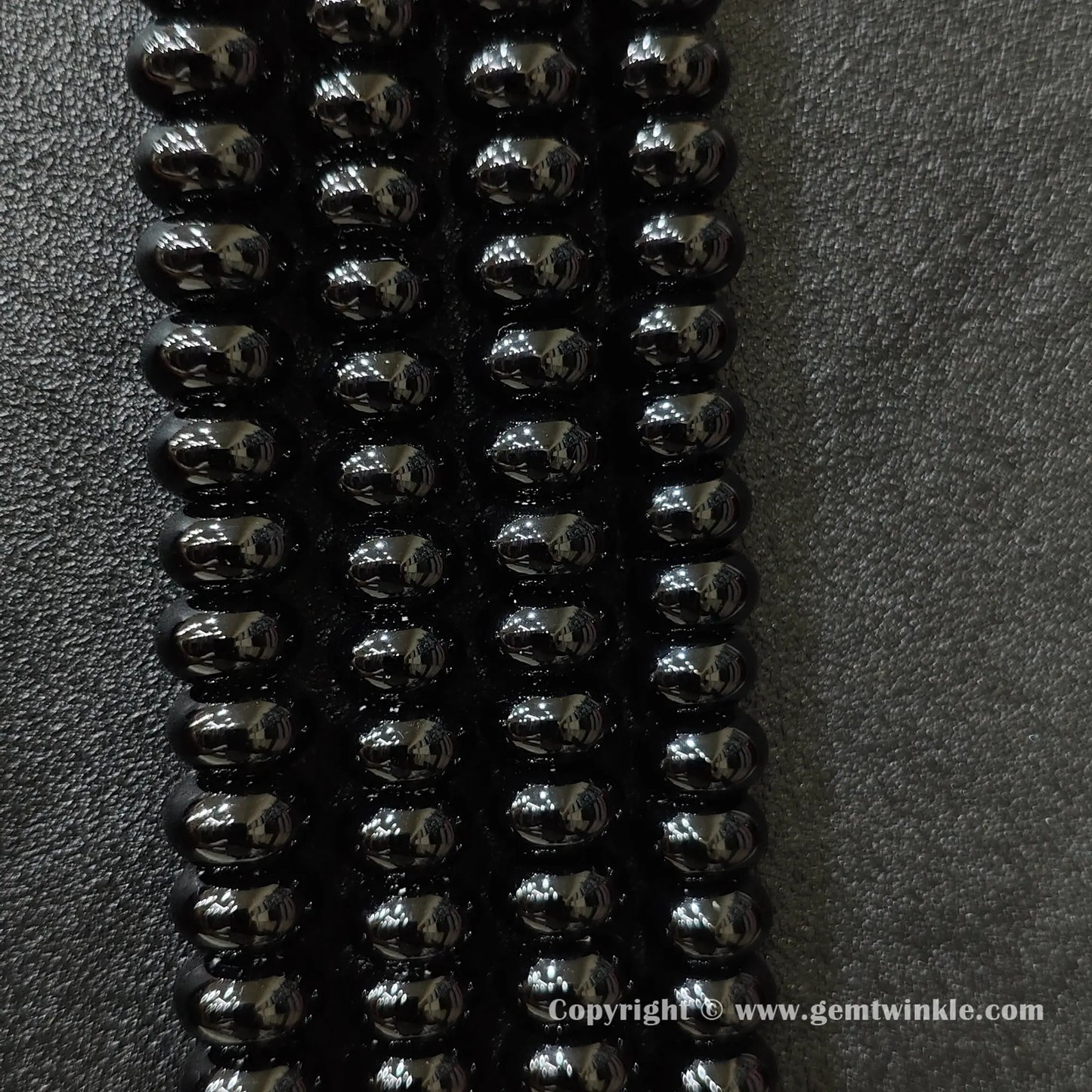 Perspective view of black agate smooth heishi spacer beads showing uniform disc thickness across strands