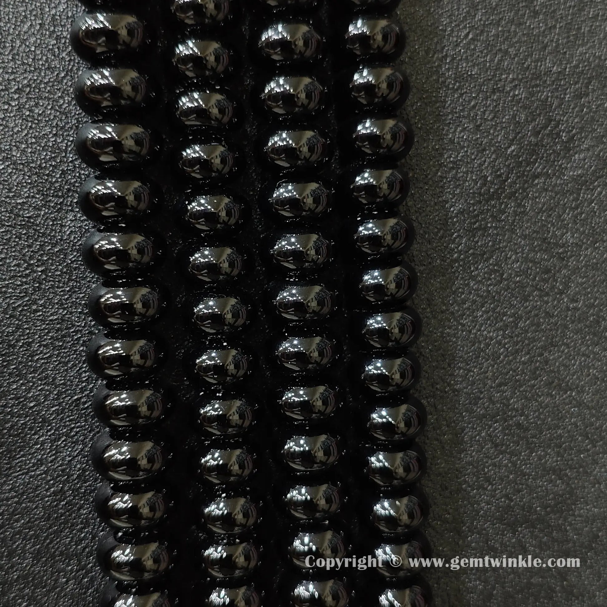 Perspective view of black agate smooth heishi spacer beads showing uniform disc thickness across strands