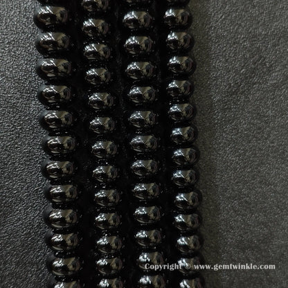 Perspective view of black agate smooth heishi spacer beads showing uniform disc thickness across strands