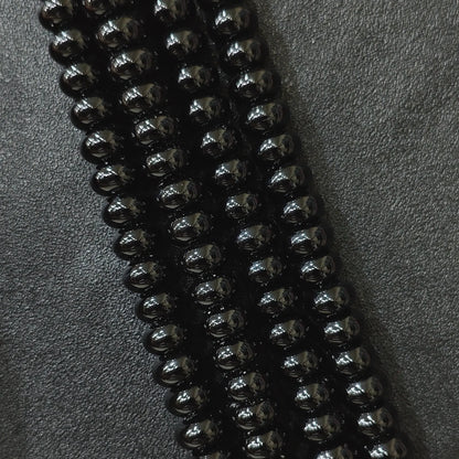 Macro closeup of color dyed black agate smooth rondelle beads in multi size strands with high gloss finish