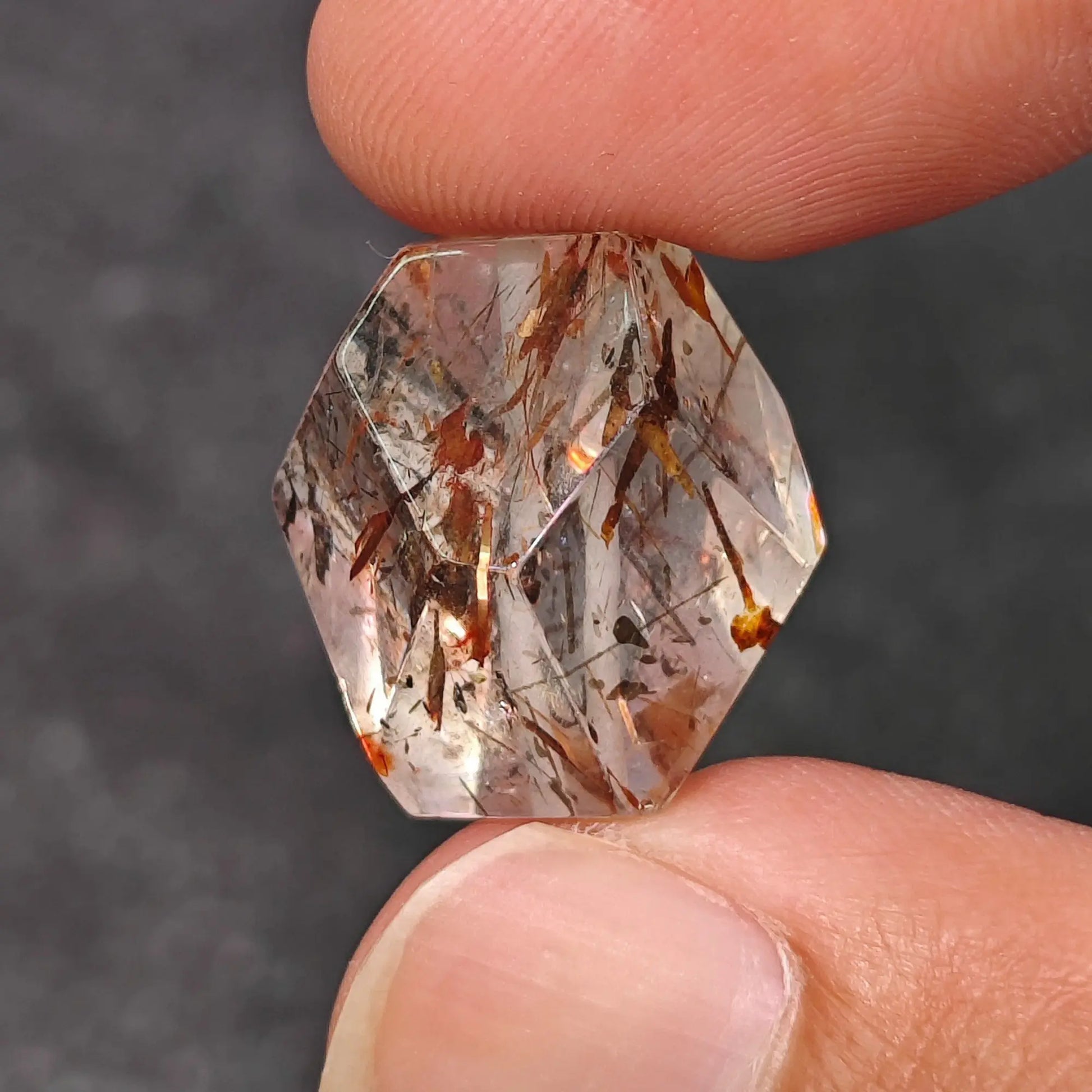 Front view of a natural black gold super seven geometric faceted nugget bead showing clear quartz matrix and dark golden inclusions