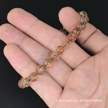close up of black gold super 7 crystal strand held across fingers