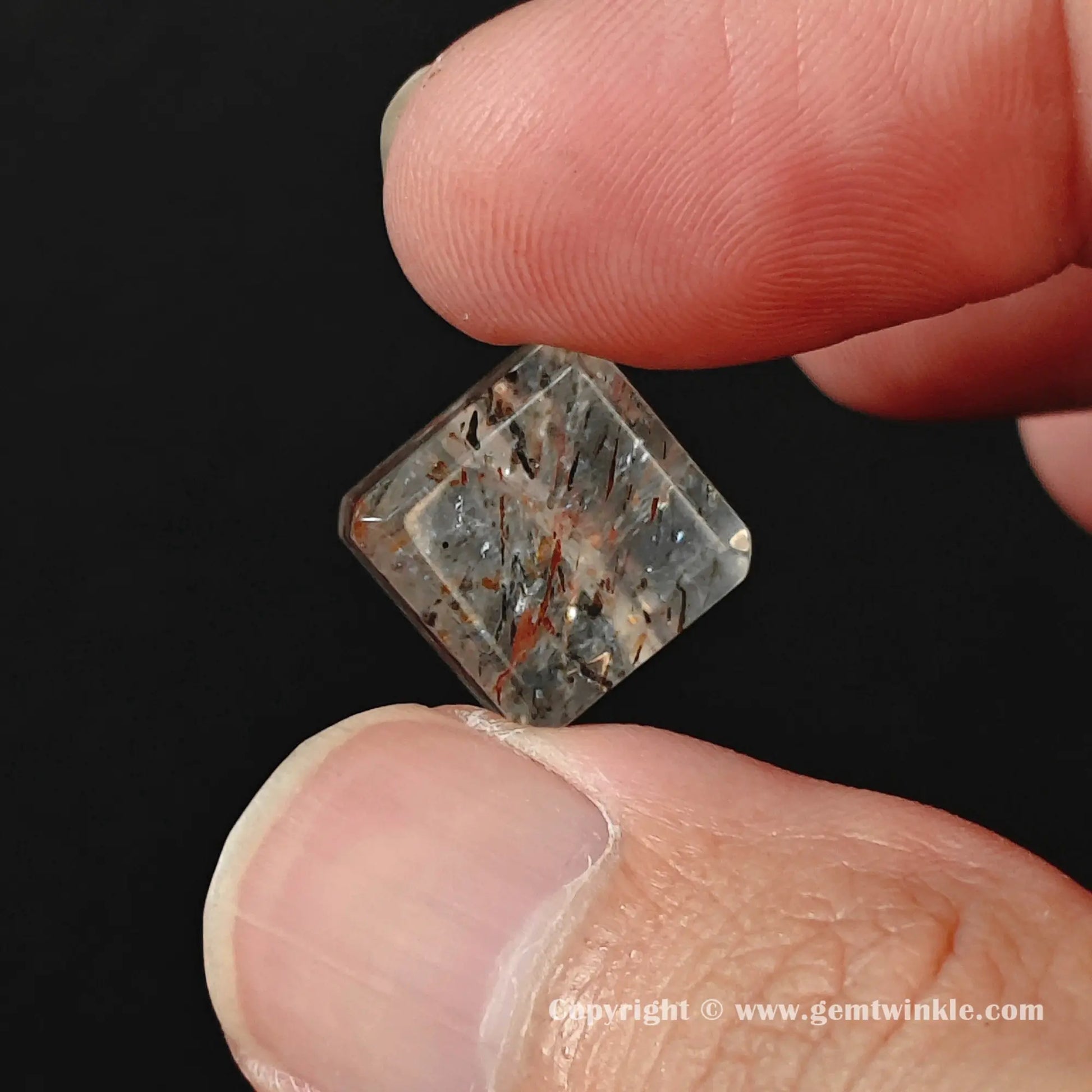 Detailed facet view of untreated black gold super seven crystal cube bead under soft lighting