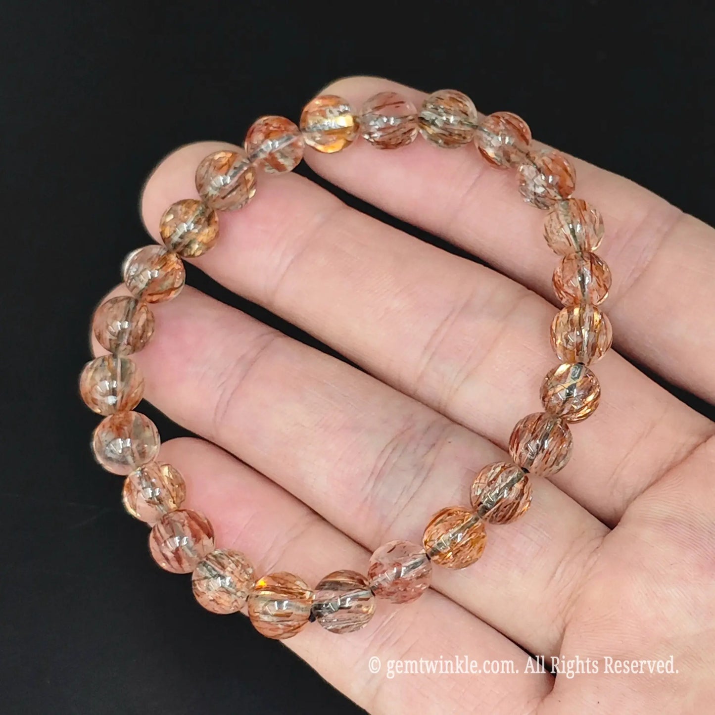 top view of 8mm black golden super seven bead stretch bangle on palm