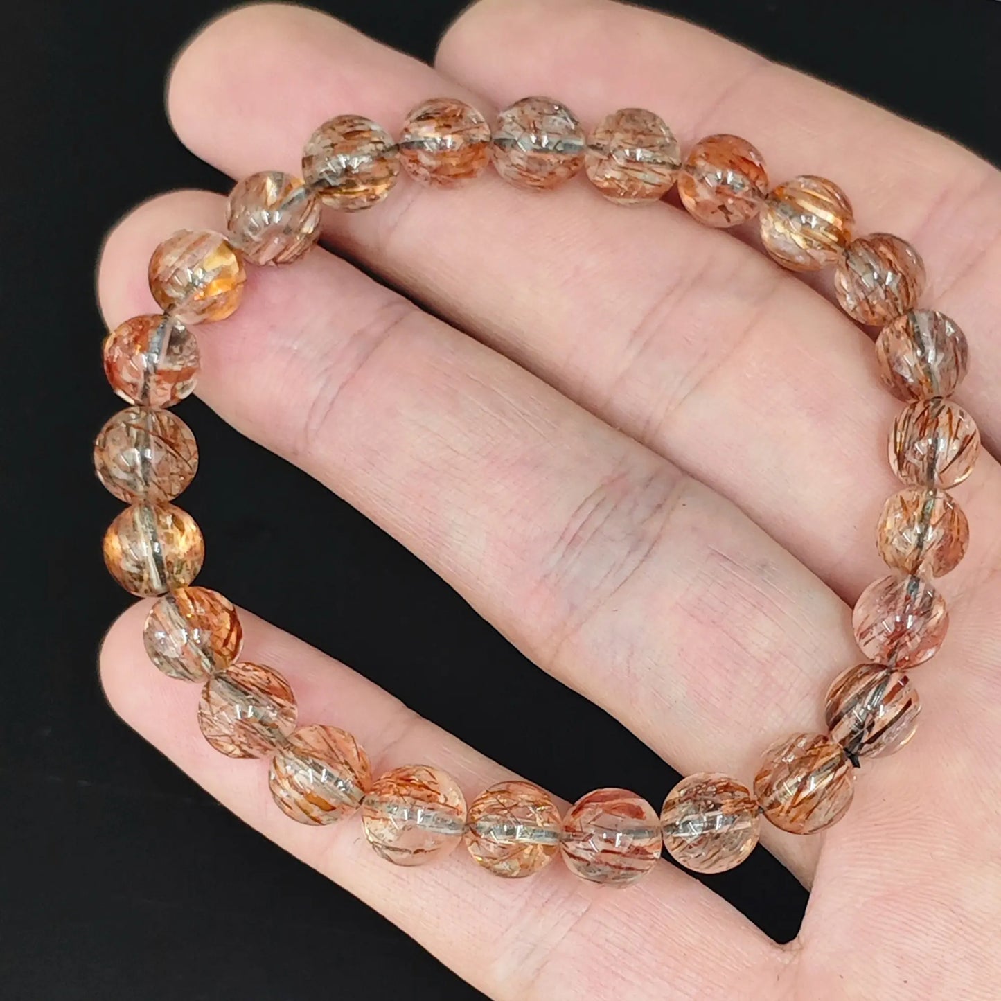 hand holding black golden super seven quartz round beads stretch bracelet