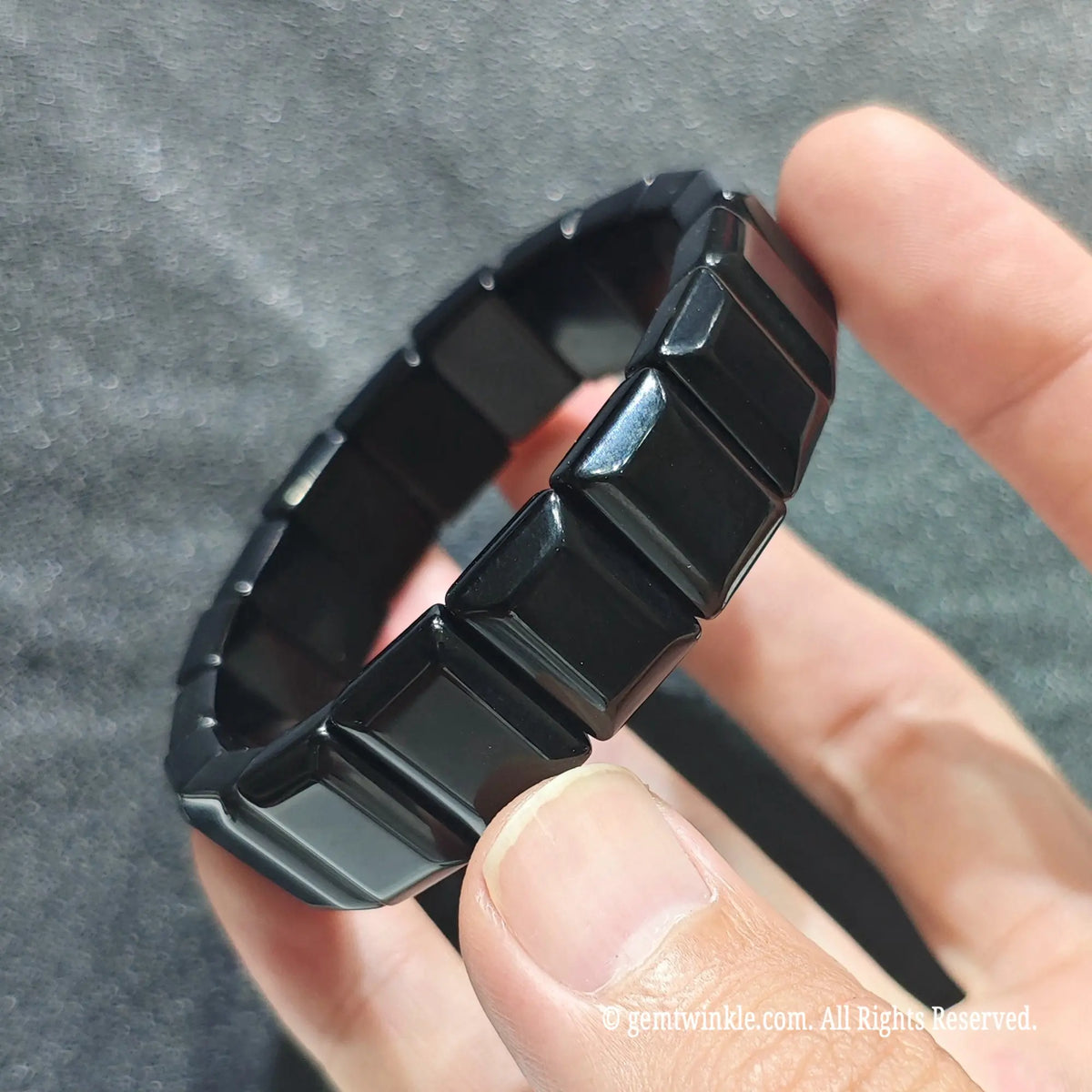 Side angle view of a black obsidian bar cut wristband displaying sleek jet black rectangular beads