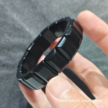 Side angle view of a black obsidian bar cut wristband displaying sleek jet black rectangular beads