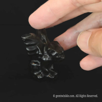 Side profile of carved black obsidian gargoyle figurine showing detailed bat wing textures