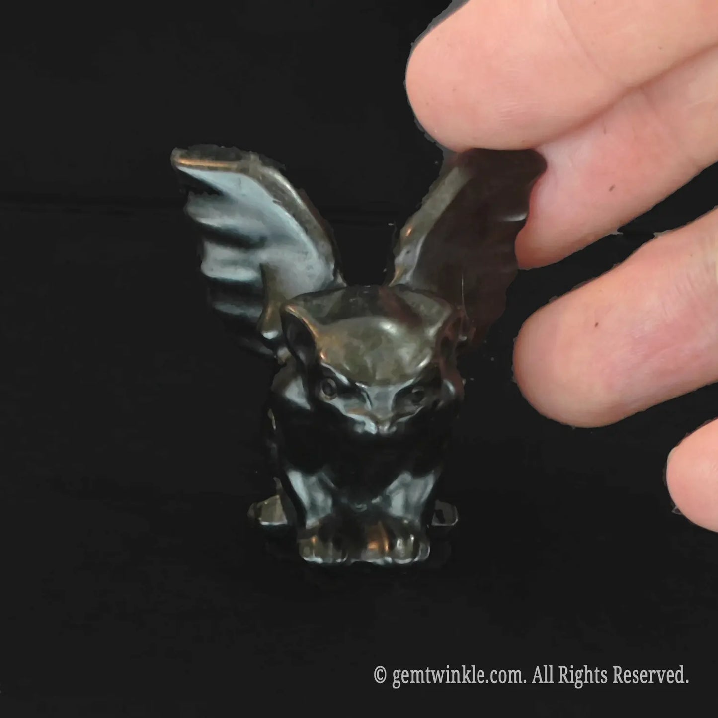 Front view of crouching black obsidian gargoyle statue with polished luster