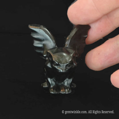 Front view of crouching black obsidian gargoyle statue with polished luster