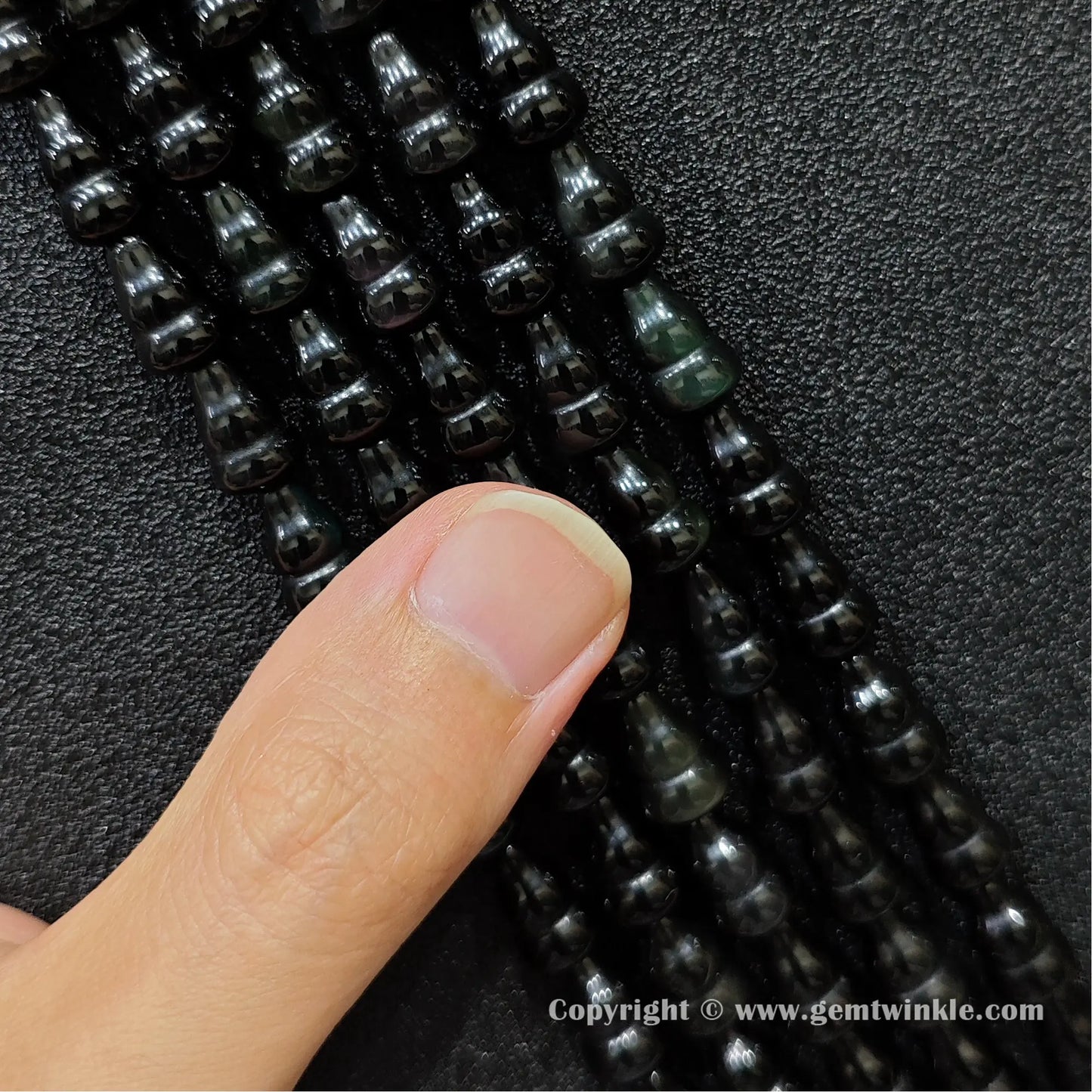 Natural black obsidian gourd bead strand held over hand showing size scale