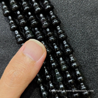 Close up view of natural black obsidian calabash beads held on fingers for quality preview