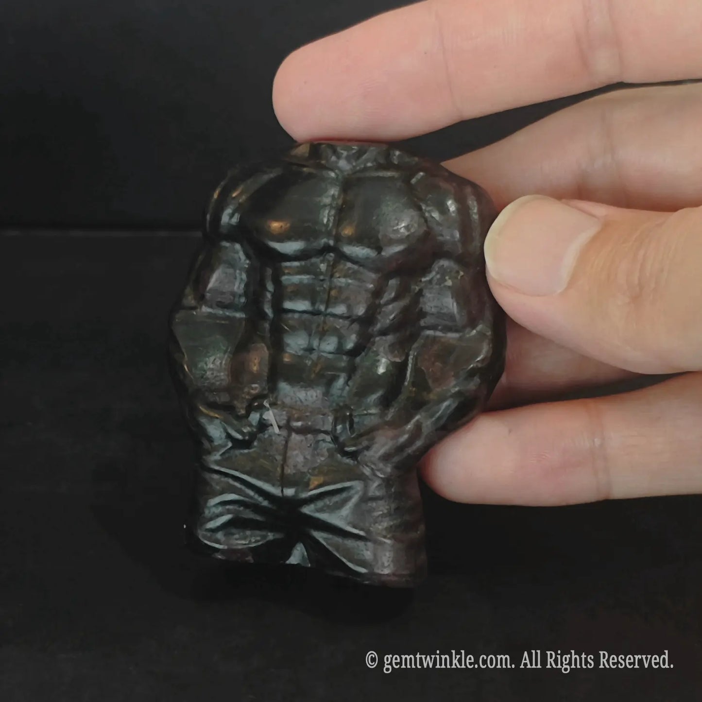 Front view of carved dark stone muscle man fitness body sculpture with polished luster