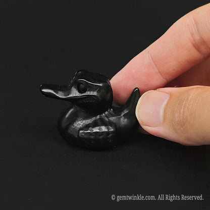 Handheld view of a 4cm glossy Black Obsidian pocket crocodile totem demonstrating miniature scale for crystal gift shop stock