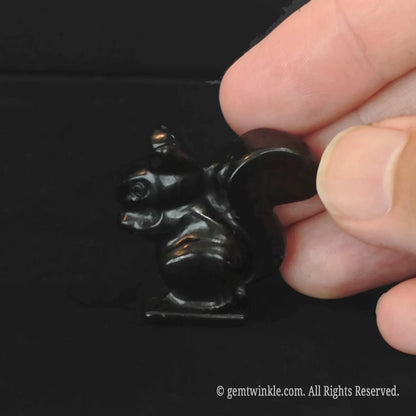 Side view of polished black obsidian squirrel figurine with a glossy reflective surface