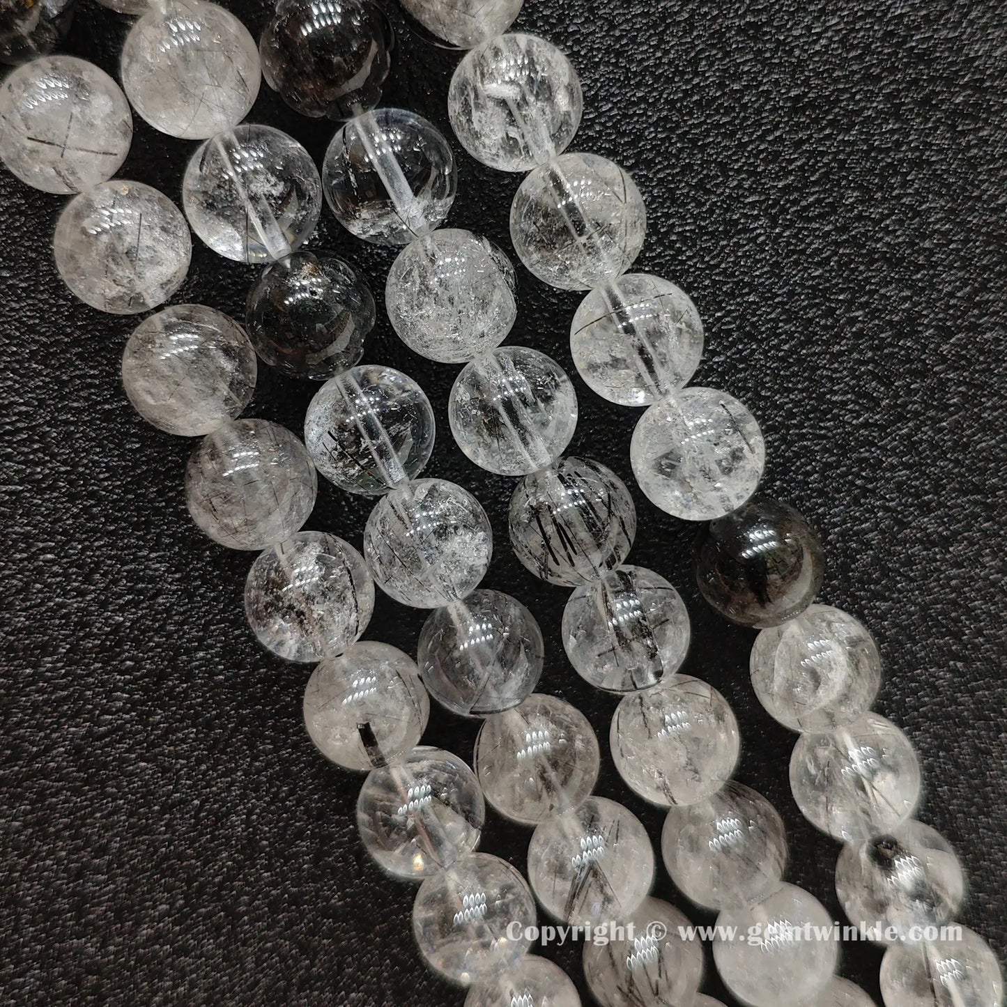 Detailed perspective of real black rutilated quartz beads in 5mm, 9mm, 11mm, and 13mm sizing options strung on jewelry wire