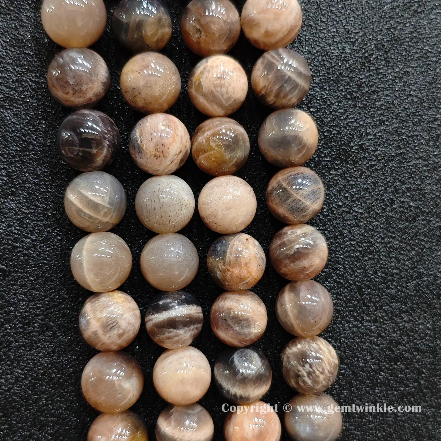 Perspective view of black sunstone round beads showing uniform spherical polish across sizes