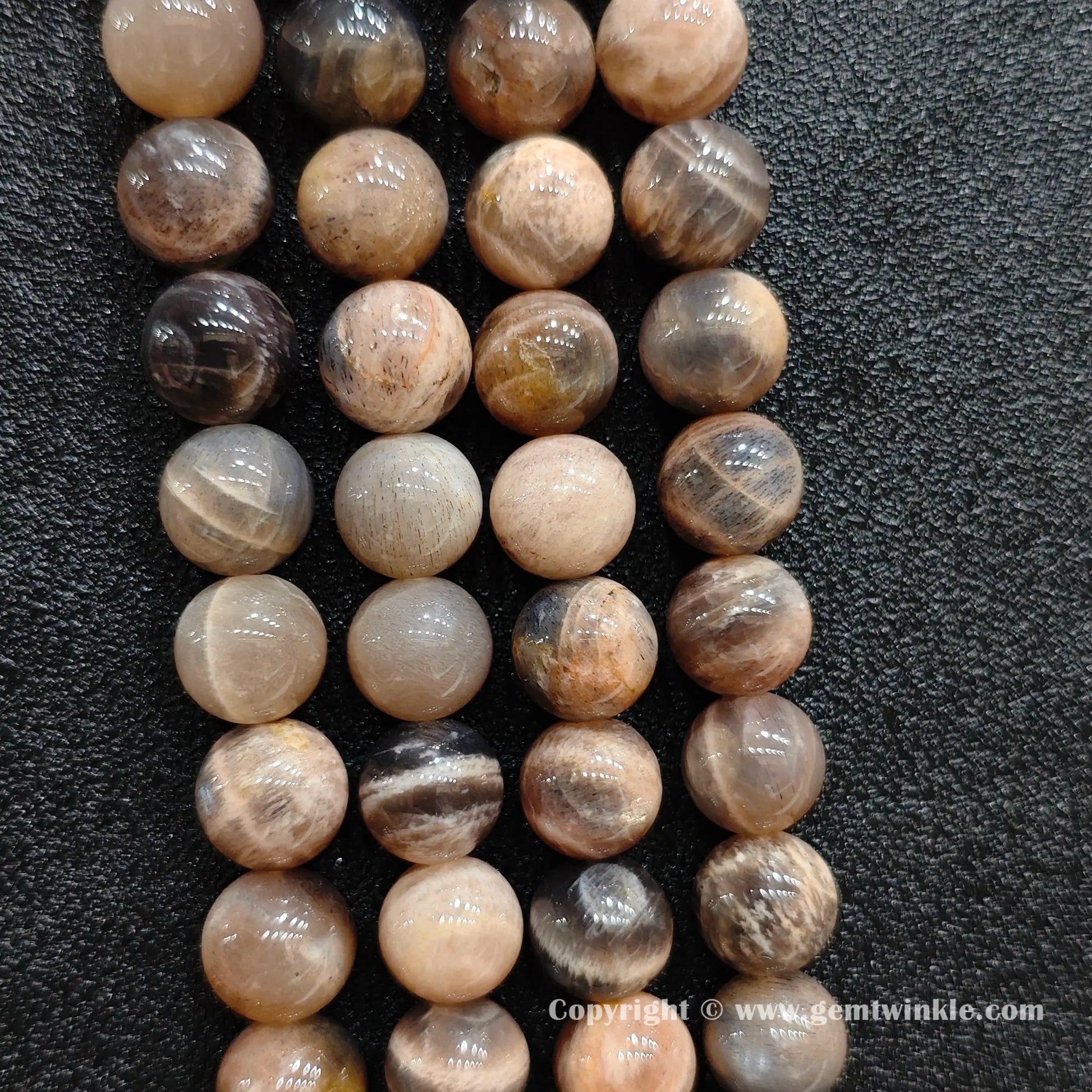 Perspective view of black sunstone round beads showing uniform spherical polish across sizes