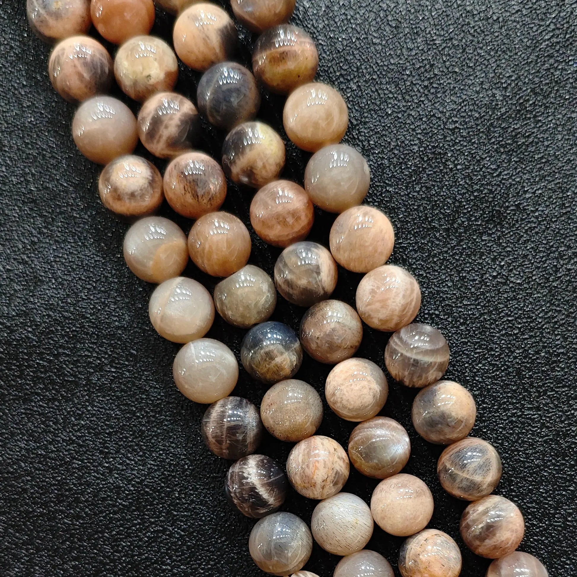 Macro closeup of natural black sunstone smooth round beads displaying metallic schiller sheen
